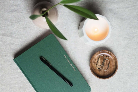 Full Focus Wellness Planner on desk with pen and candle